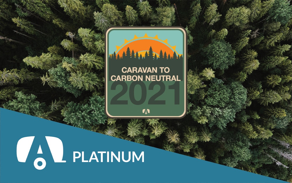 Platinum tag with the Caravan to Carbon Neutral sticker on a tree background